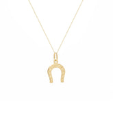 A delicate gold chain necklace featuring a small horseshoe pendant with tiny engraved stars, displayed against a solid white background.