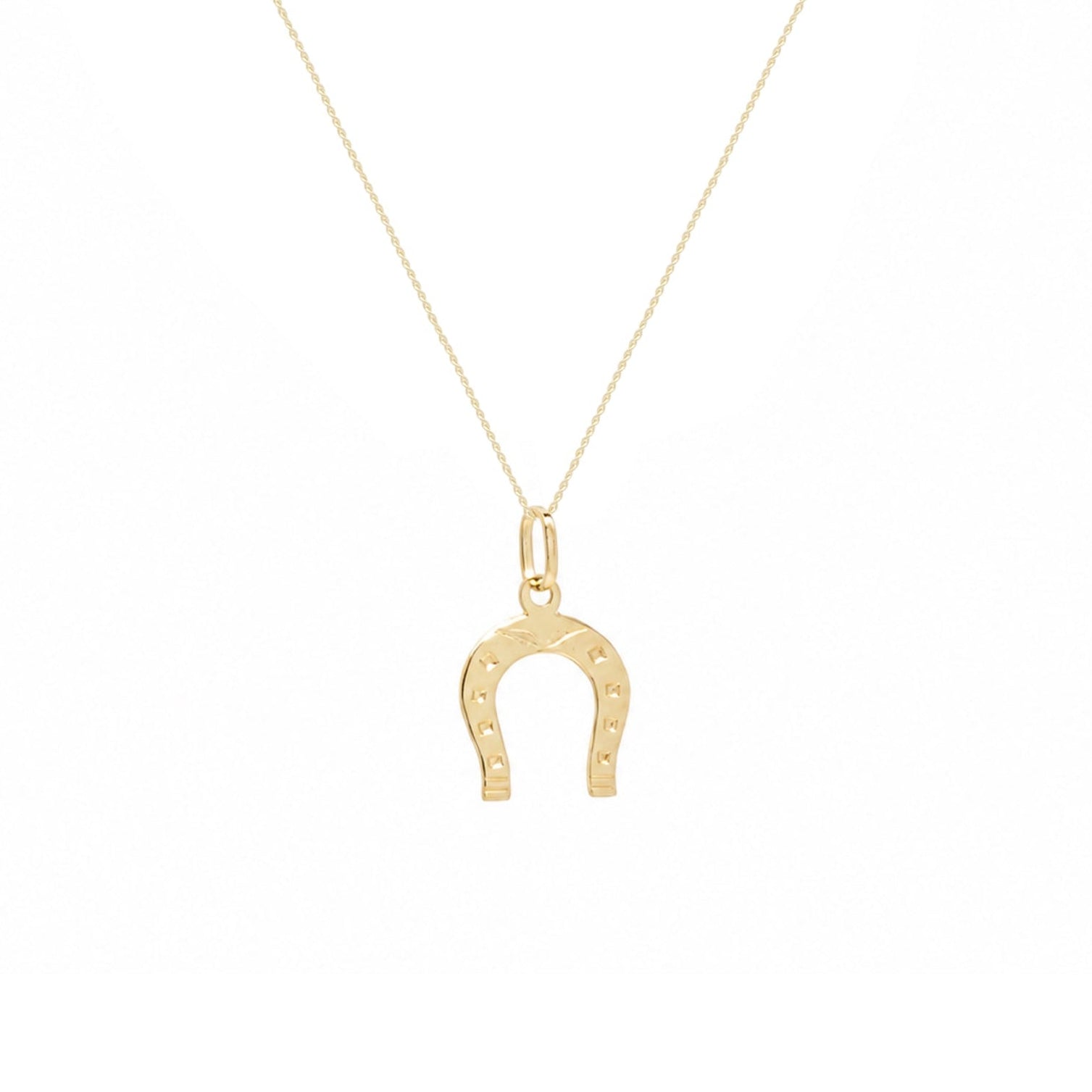 A delicate gold chain necklace featuring a small horseshoe pendant with tiny engraved stars, displayed against a solid white background.